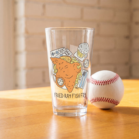 Fried-Ray Fish Fry Pint Glass on a wood table next to a baseball