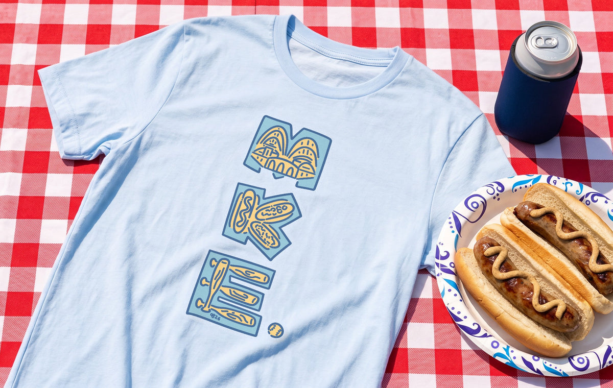MKE Ballpark tee in Light Blue on a red checked tailgate tablecloth with brats